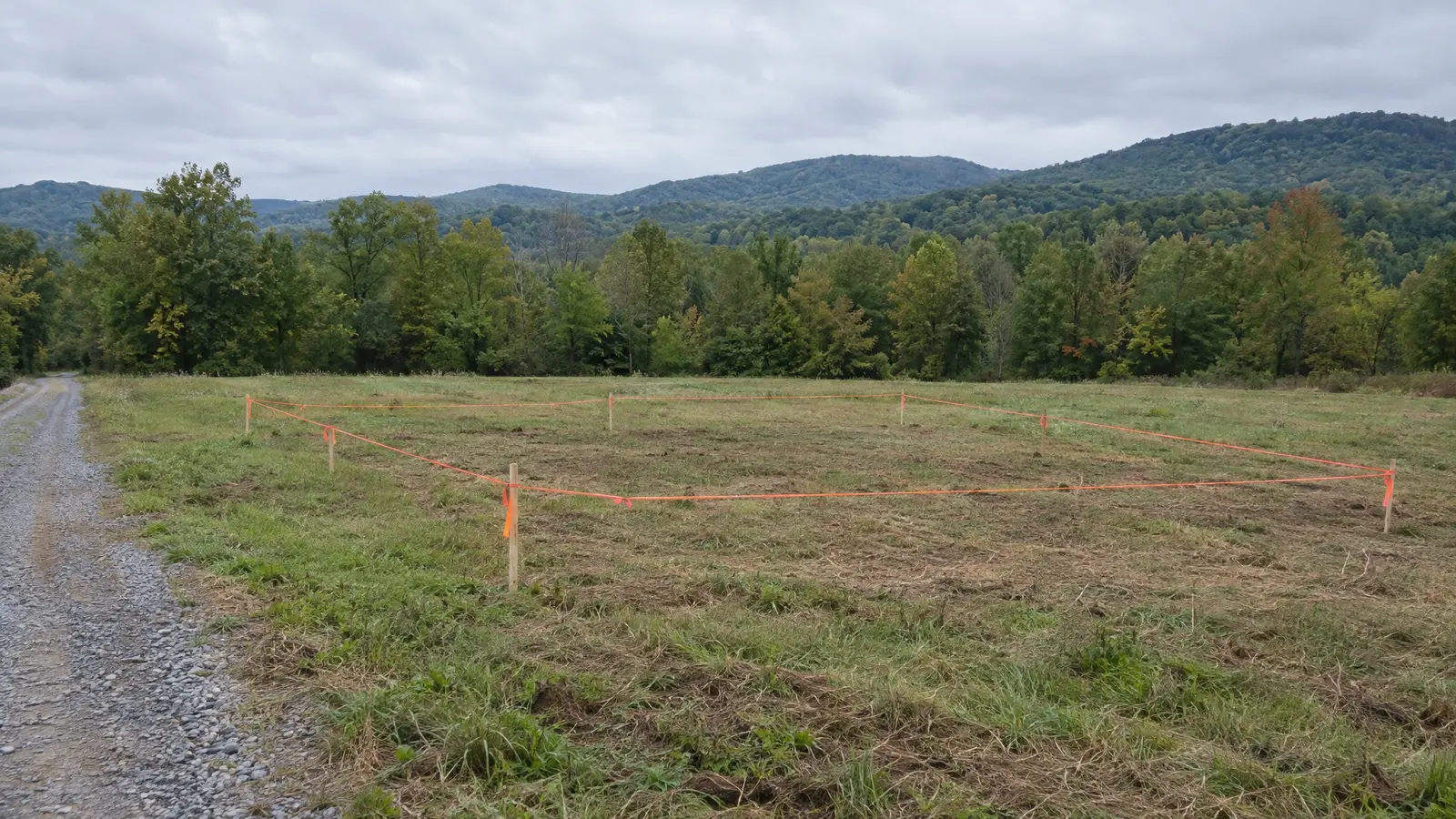 Before: a staked building site with an empty grassy field with survey stakes